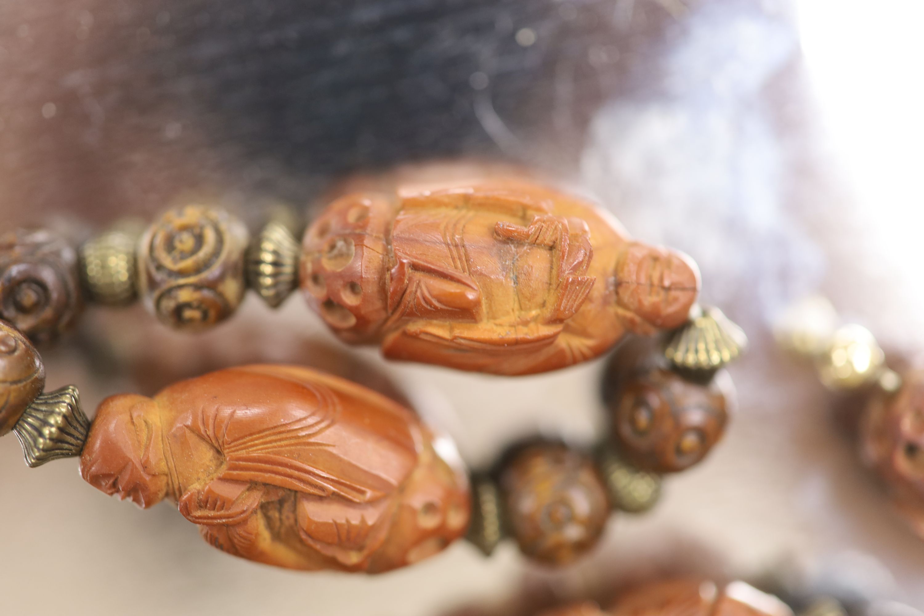 A Chinese peach stone or nut bead necklace, bracelet, a pair of earrings and two carved beads